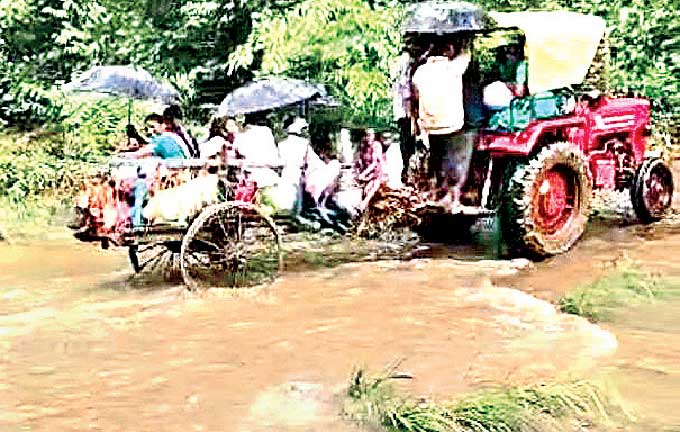 ట్రాక్టర్కు ట్రాలీకి బదులుగా ఎడ్లబండిని కట్టుకుని, మరో ట్రాక్టర్లో నిండుగా కూర్చుని వాగులు దాటుతున్న వీరంతా.. మండలంలోని ఇస్లాంపూర్ గిరిజనులు. ఆ ఊరికి రహదారి వసతి లేదు. మంచిర్యాల జిల్లా జన్నారం మండలం కవ్వాల్ నుంచి అటవీమార్గంలో 9కిలోమీటర్లు ప్రయాణిస్తే ఈ గ్రామం వస్తుంది. ఆషాఢ మాసంలో కవ్వాల్ పోచమ్మతల్లి ఆలయంలో పాడిపంట, పిల్లాపాప బాగుండాలని ఈ గ్రామ గిరిజనులు పూజలు చేస్తుంటారు. మంగళవారం వెళ్దామంటే భారీ వర్షం కురవడంతో వాగులు పొంగాయి. దీంతో ఇలా ట్రాక్టర్ల ద్వారా వాగులు దాటి వెళ్లి పూజల్లో పాల్గొన్నారు.